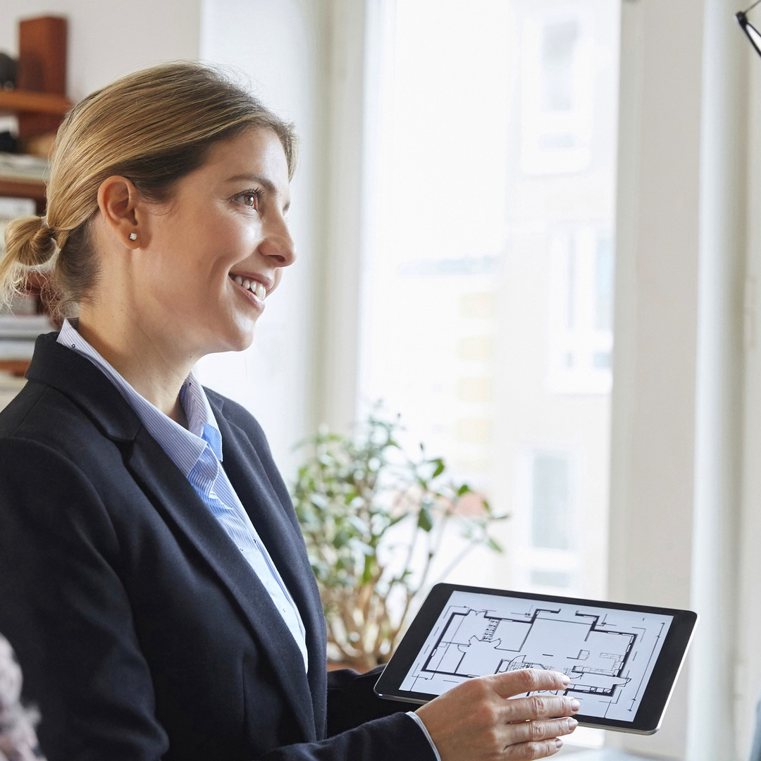Mäklare som visar en planlösning på en ipad